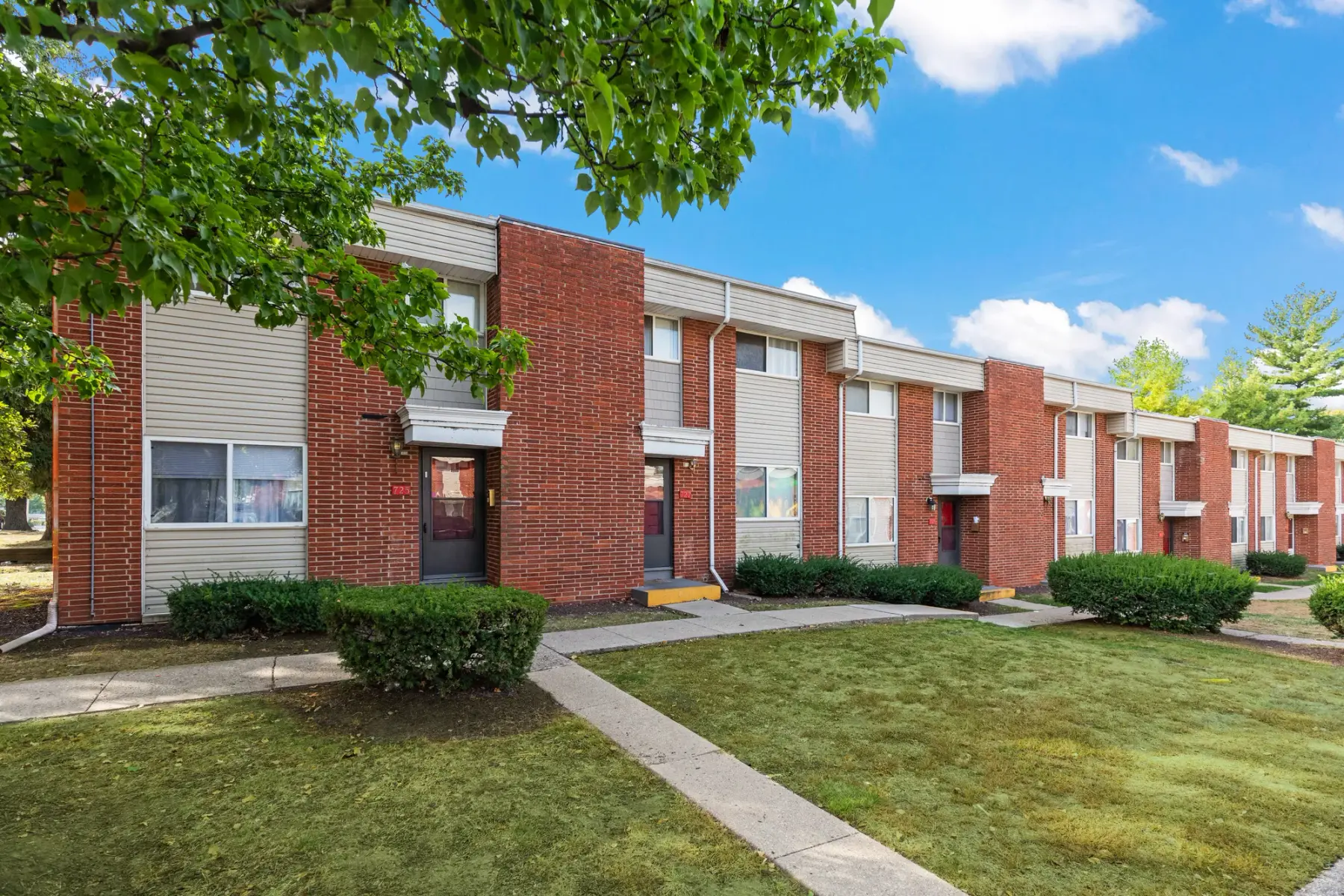 Row of two-story brick townhomes at Westbury, each with its own private front entry and walkway